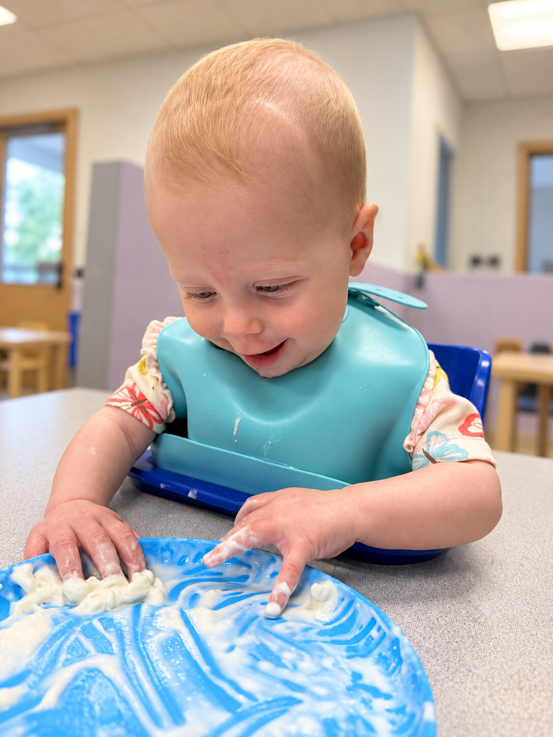 Smiling infant exploring a sensory activity with both hands