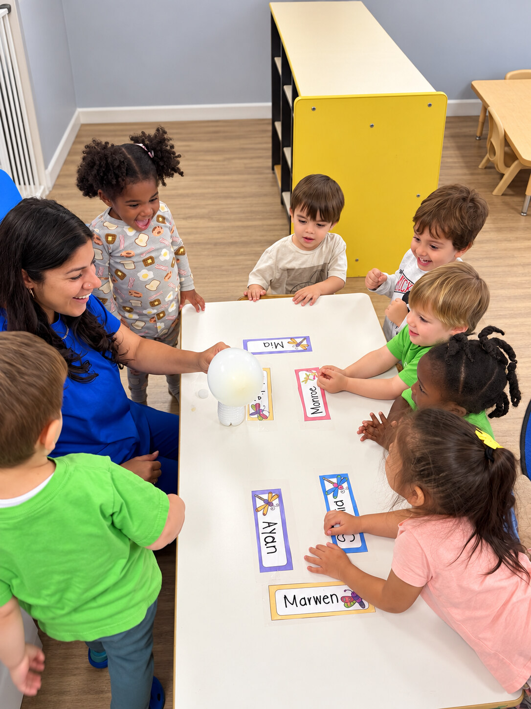 Teacher and children exploring a light experiment at a classroom table
