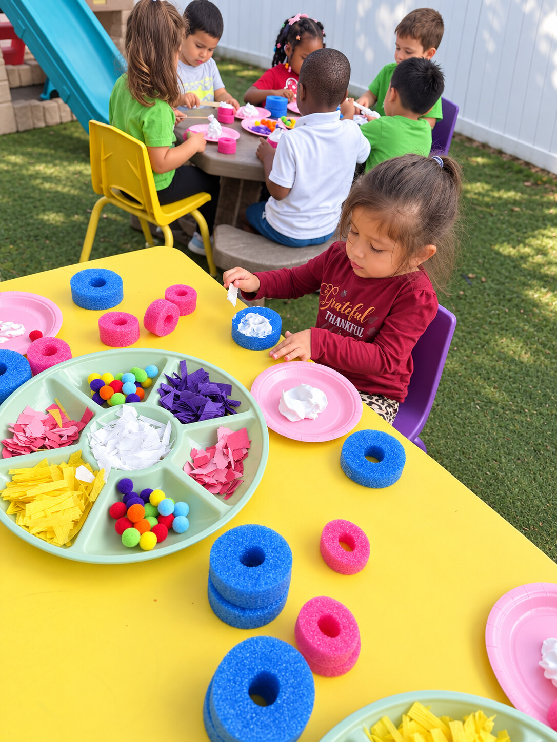 Children making colorful crafts together outdoors at Sunshine