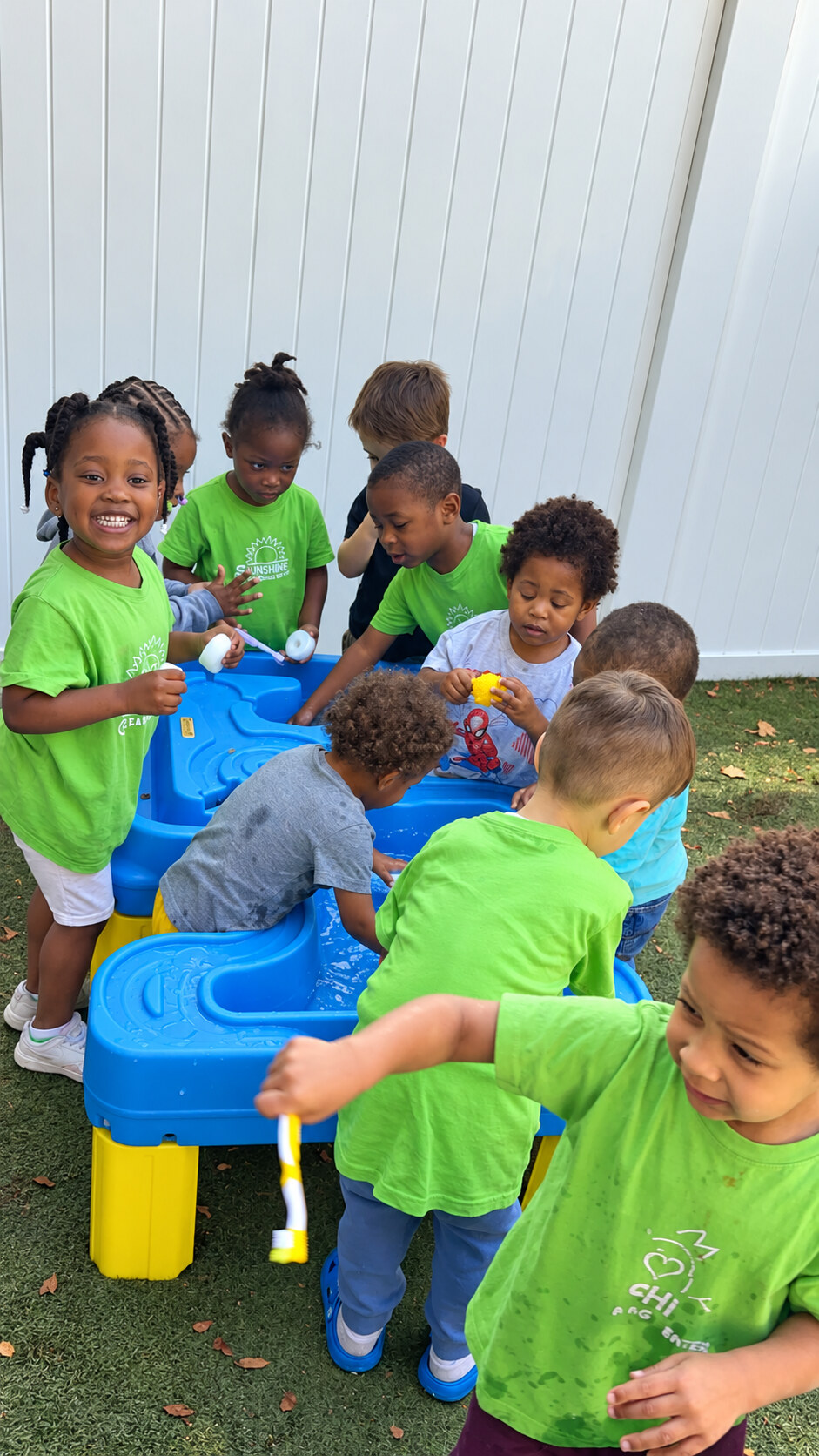 Children gathered around an outdoor water play table